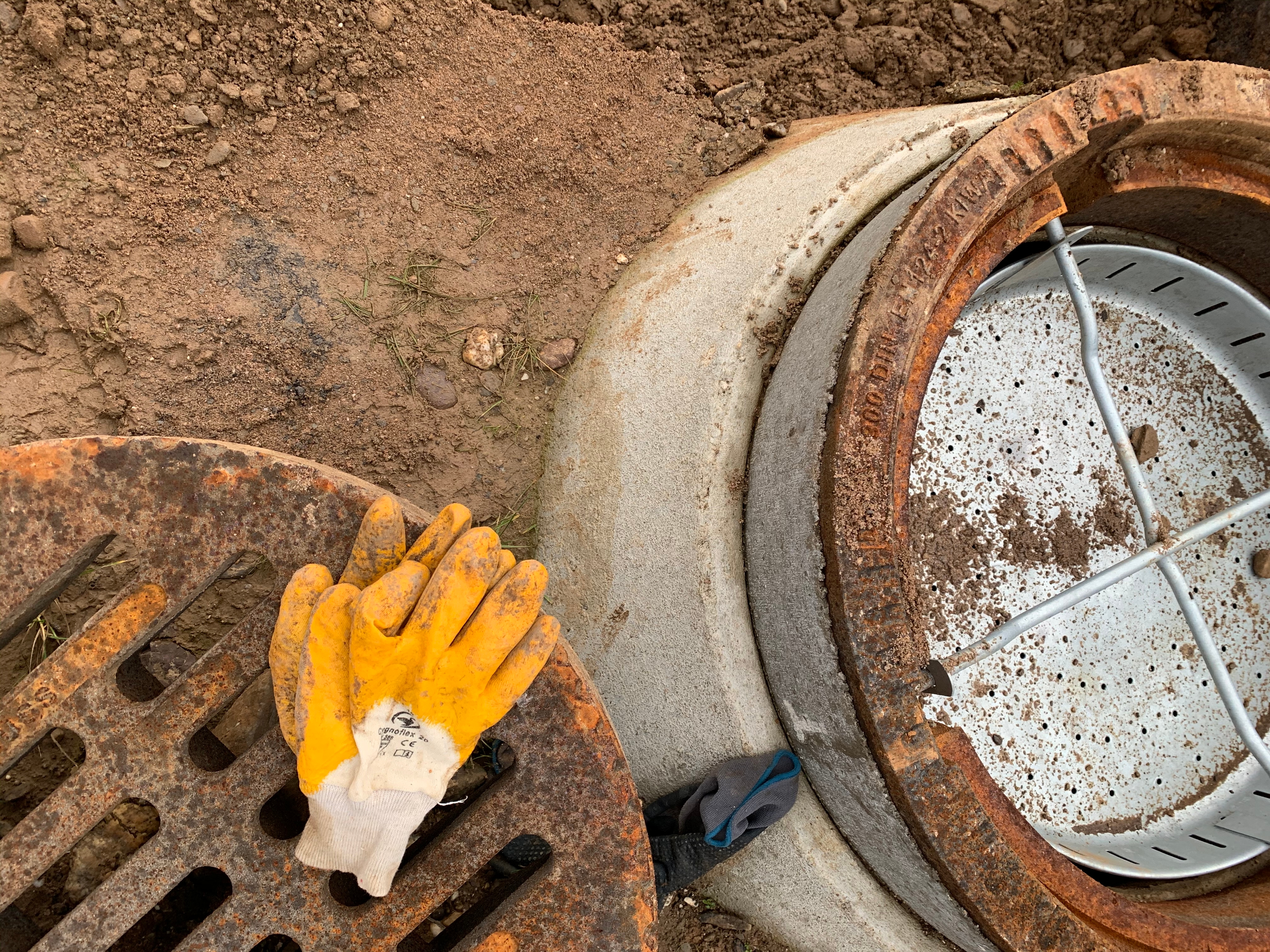 Neu eingebauter Gulli, daneben Arbeitshandschuhe