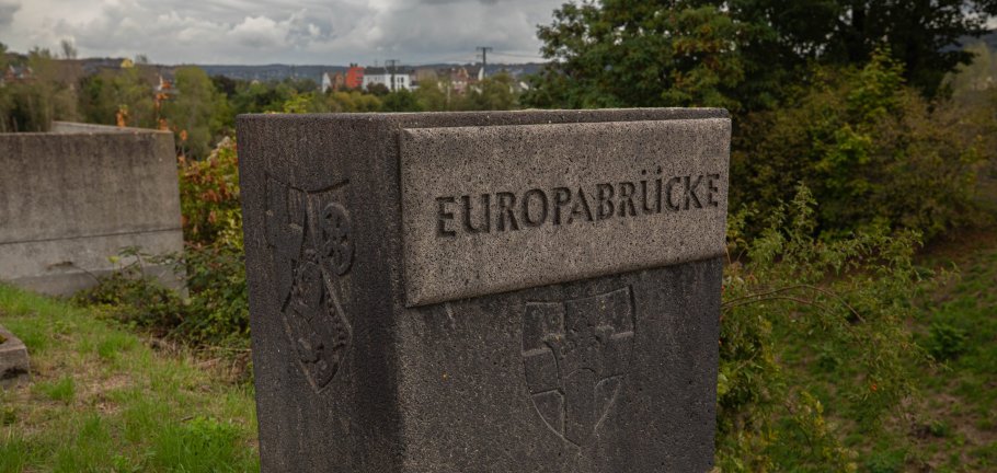Ein Stein mit der Inschrift "Europabrücke" steht auf einer Wiese. Ein Stein mit der Inschrift "Europabrücke" steht auf einer Wiese.