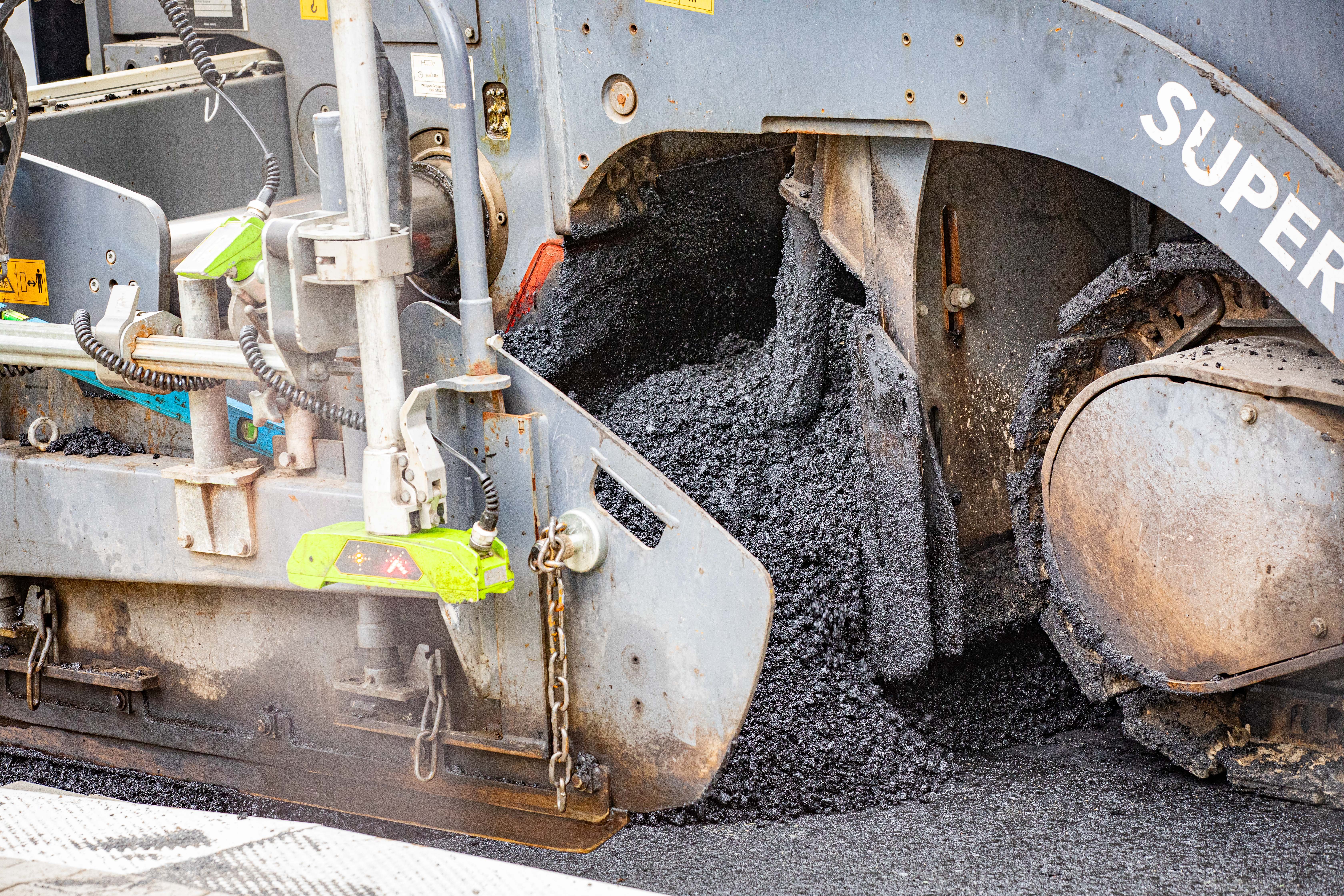 Der Asphalt wird verarbeitet und als neue Fahrbahndecke aufgetragen.  Der Asphalt wird verarbeitet und als neue Fahrbahndecke aufgetragen.