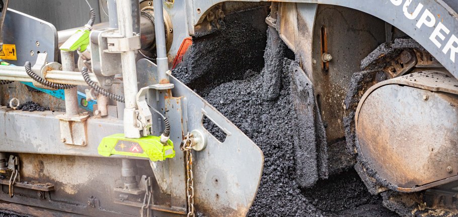 Der Asphalt wird verarbeitet und als neue Fahrbahndecke aufgetragen. 