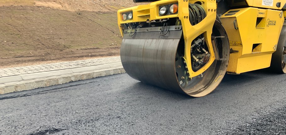 Eine Walze verhärtet den frischen Asphalt. Eine Walze verhärtet den frischen Asphalt.