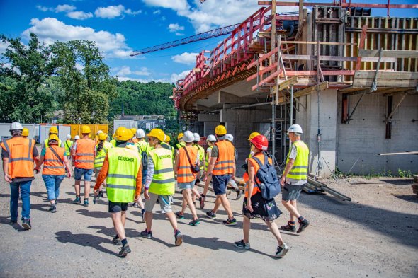 Eine Besuchergruppe in Warnwesten läuft über eine Baustelle. Eine Besuchergruppe läuft über eine Baustelle.
