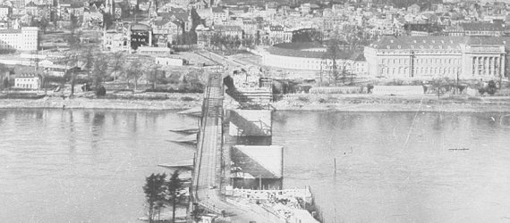 Das Bild zeigt die Brückenpfeiler der neuen Pfaffendorfer Brücke, daneben die provisorische Behelfsbrücke.