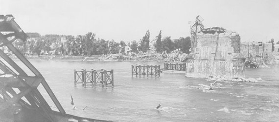 Das Bild zeigt die zerstörte Pfaffendorfer Brücke, von der auf dem Bild nur noch die Pfeiler zu sehen sind.