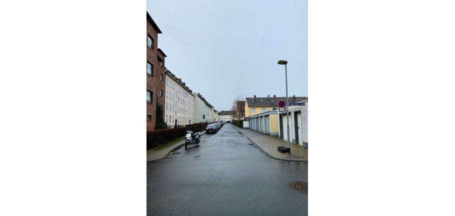 Peter-Friedhofen-Straße Einfahrt in die Peter-Friedhofen-Straße, in am linken Seitenrand Autos parken.