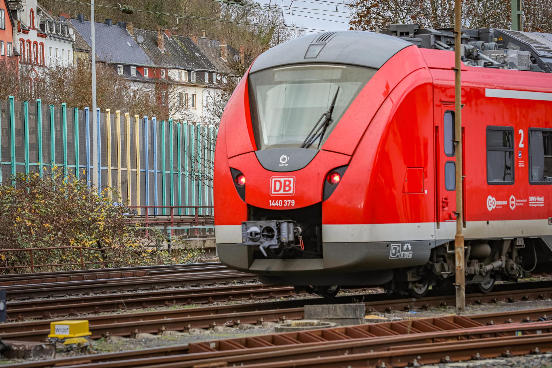 Ein Zu fährt auf Gleisen an einer Schallschutzwand vorbei.