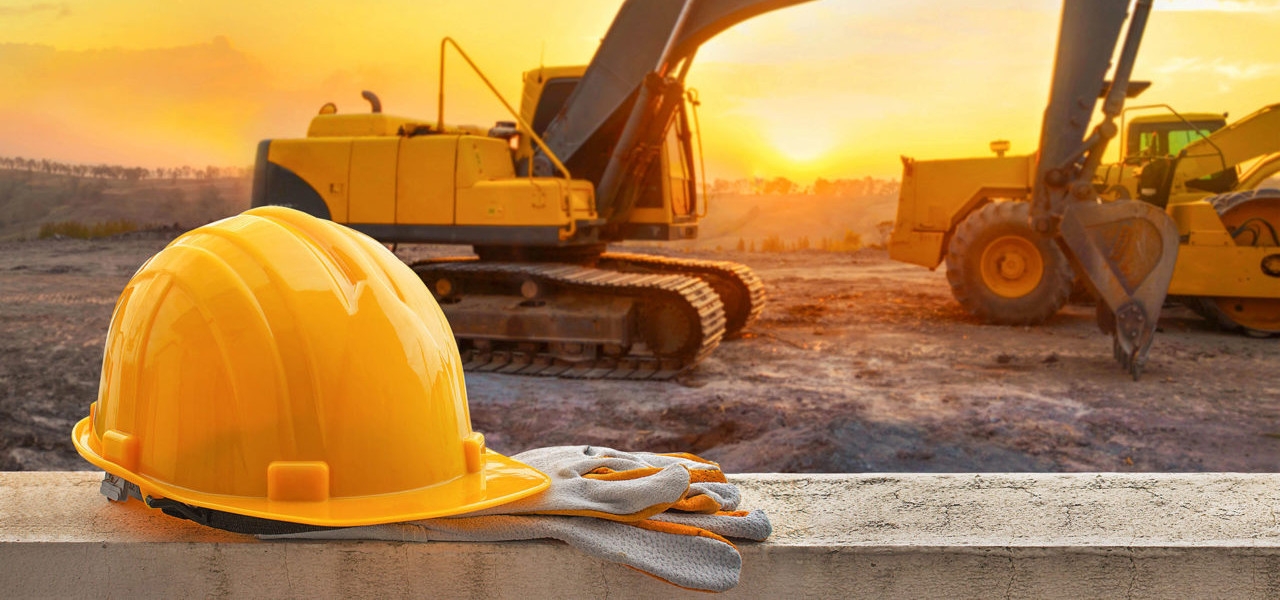 Baustellenhelm und Bagger im Sonnenuntergang