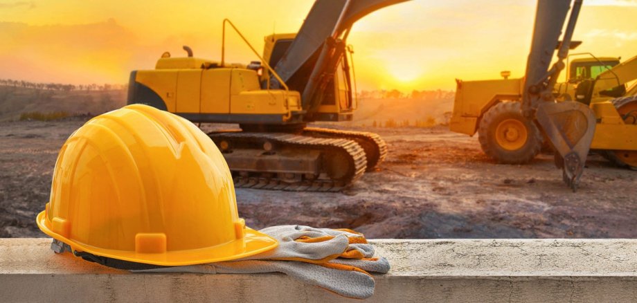 Baustellenhelm und Bagger im Sonnenuntergang Baustellenhelm und Bagger im Sonnenuntergang