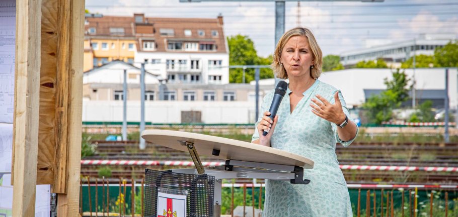 Die rheinland-pfälzische Mobilitätsministerin Katrin Eder beim Spatenstich für die Geh- und Radwegbrücke zwischen den Koblenzer Stadtteilen Goldgrube und Rauental. Eine Frau steht an einem Rednerpult.