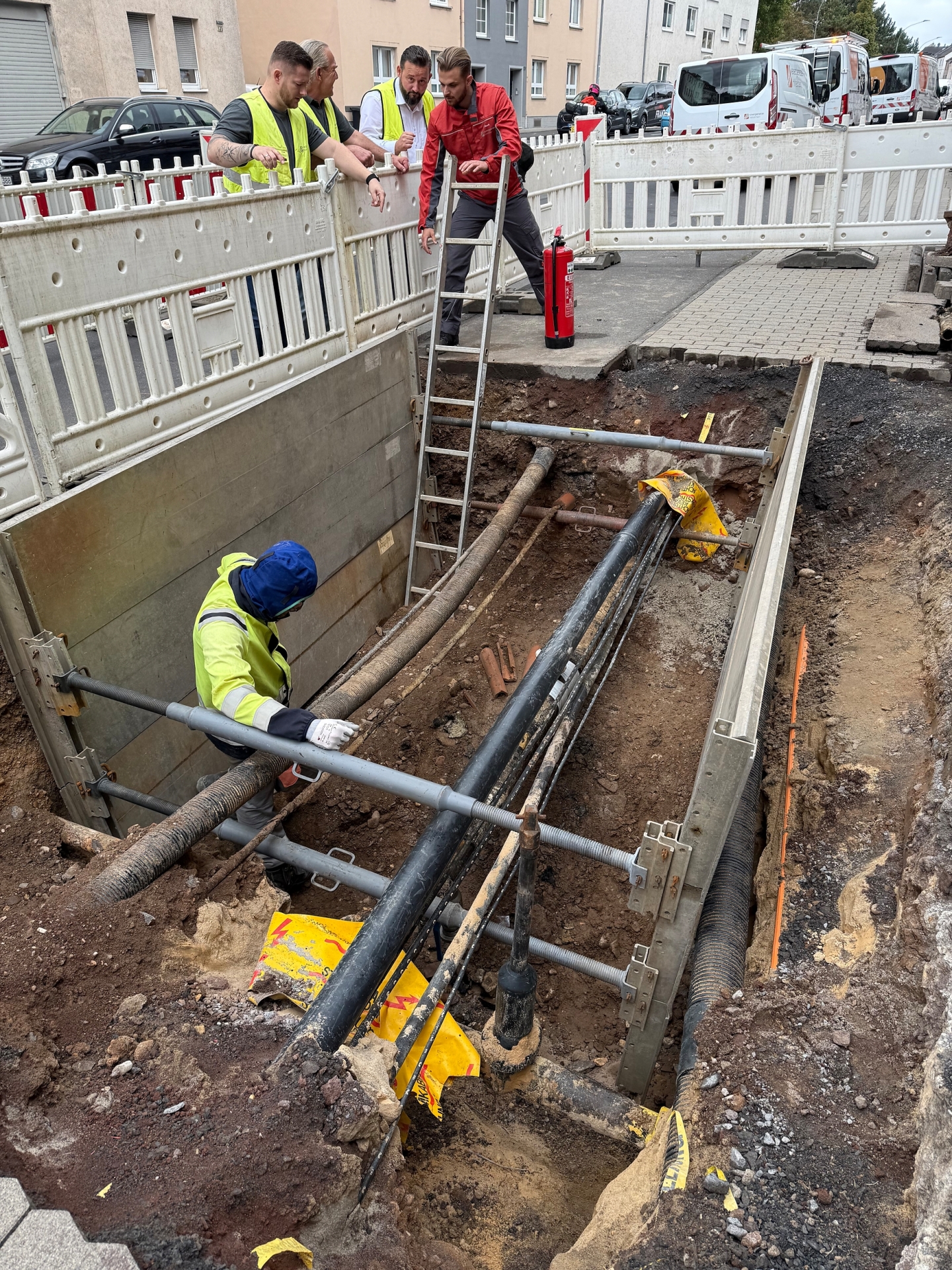 Bauarbeiter stehen an Absperrungen rund um eine Baugrube.