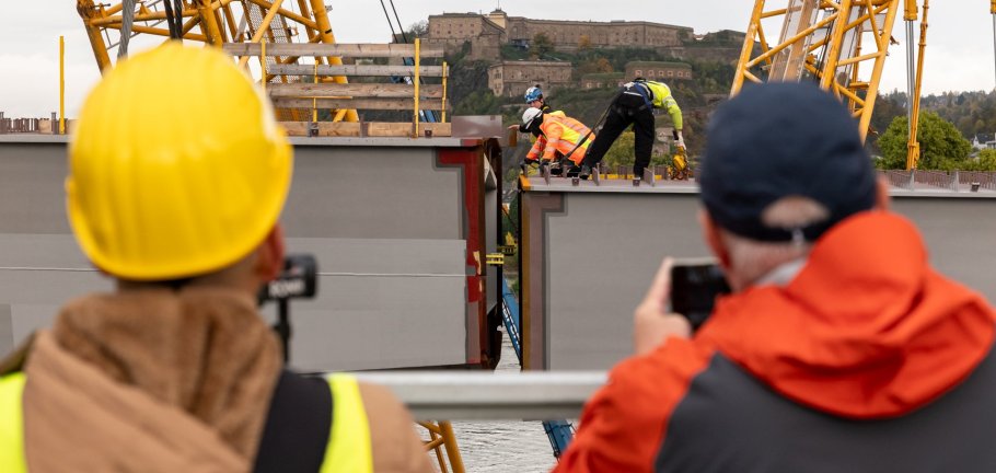 Die Einhubarbeiten für die neue Pfaffendorfer Brücke haben zahlreiche Schaulustige für Erinnerungsfotos und Videos genutzt.  Schaulustige fotografieren und filmen Bauarbeiter beim Einhub eines Stahlbauteils.