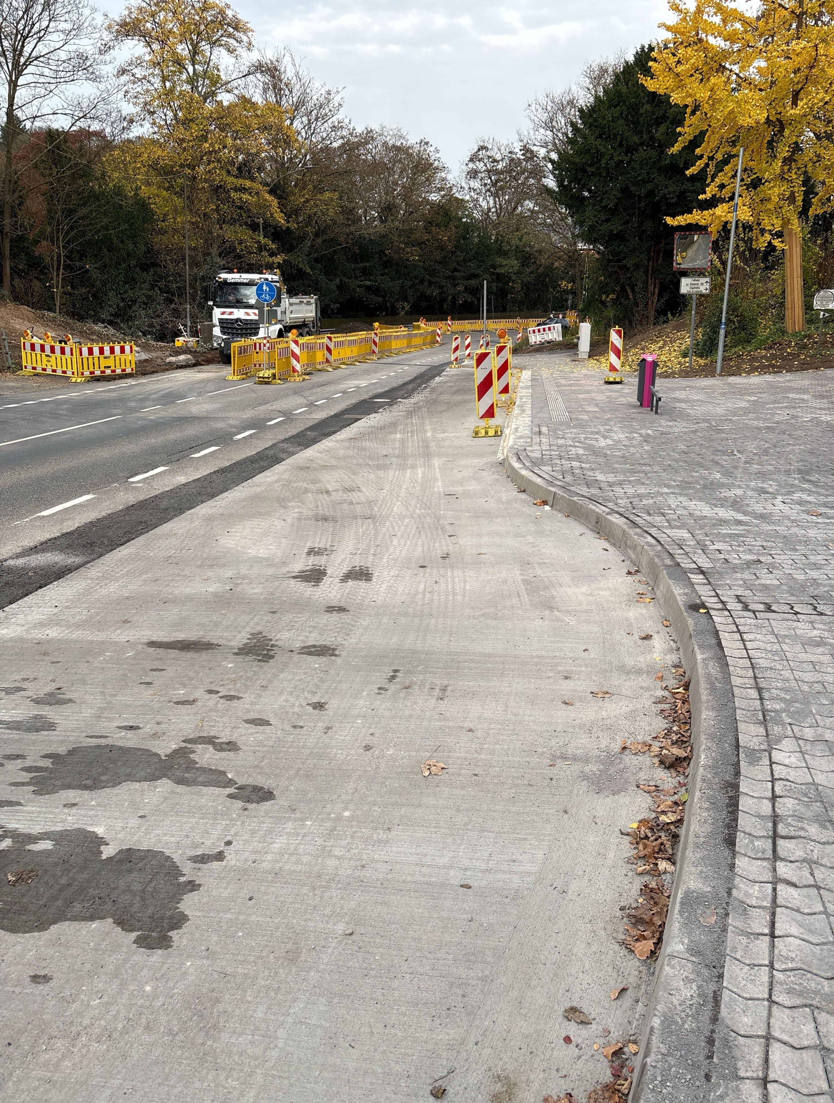 Eine Baustelle mit Absperrungen für den Fahrzeugverkehr. Außerdem ist eine fertiggestellte Bushaltestelle zu sehen.