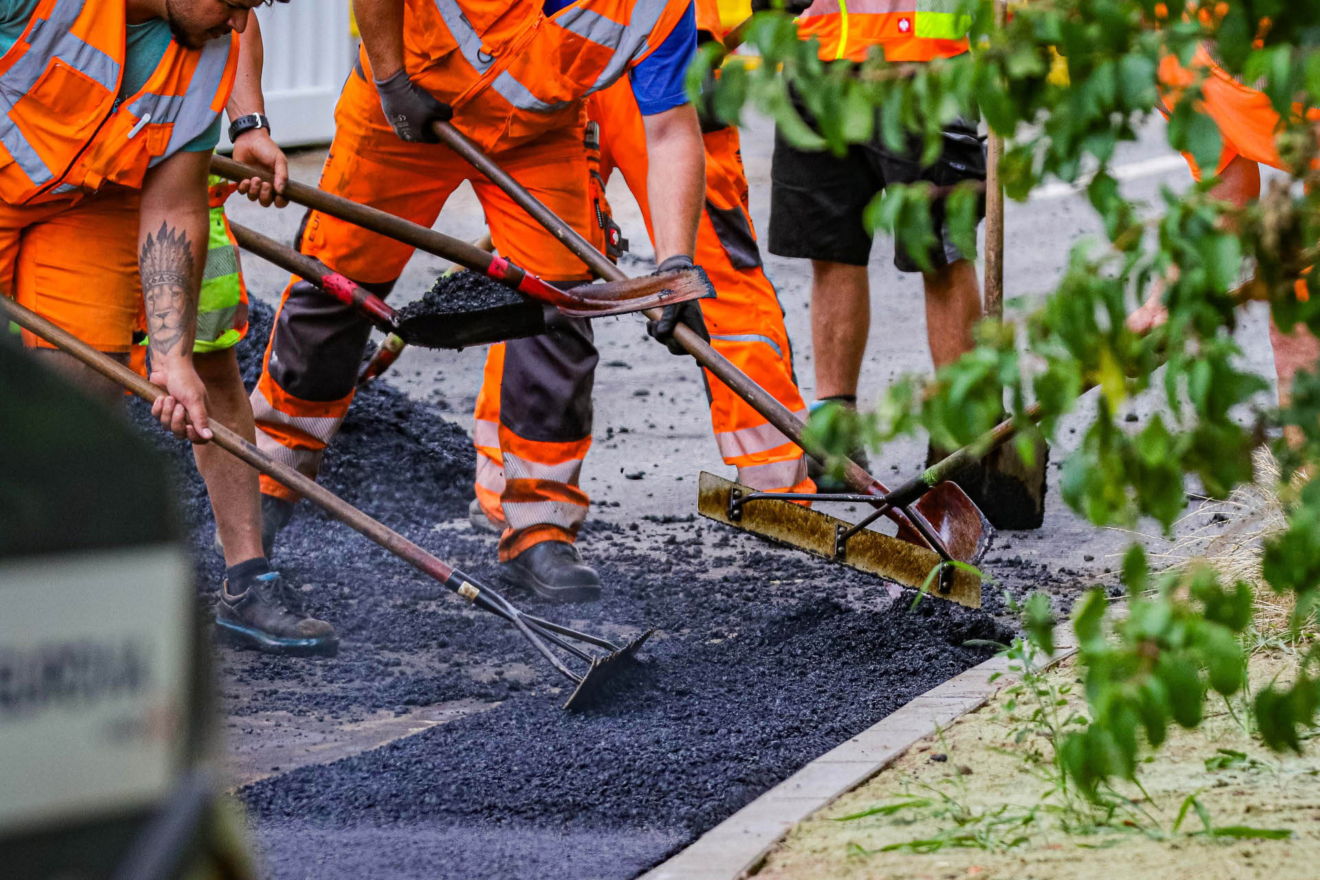 Bauarbeiter bauen Asphalt auf einer Straße ein.