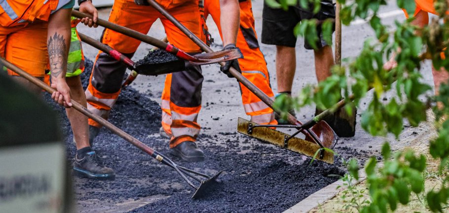Bauarbeiter bauen Asphalt auf einer Straße ein.