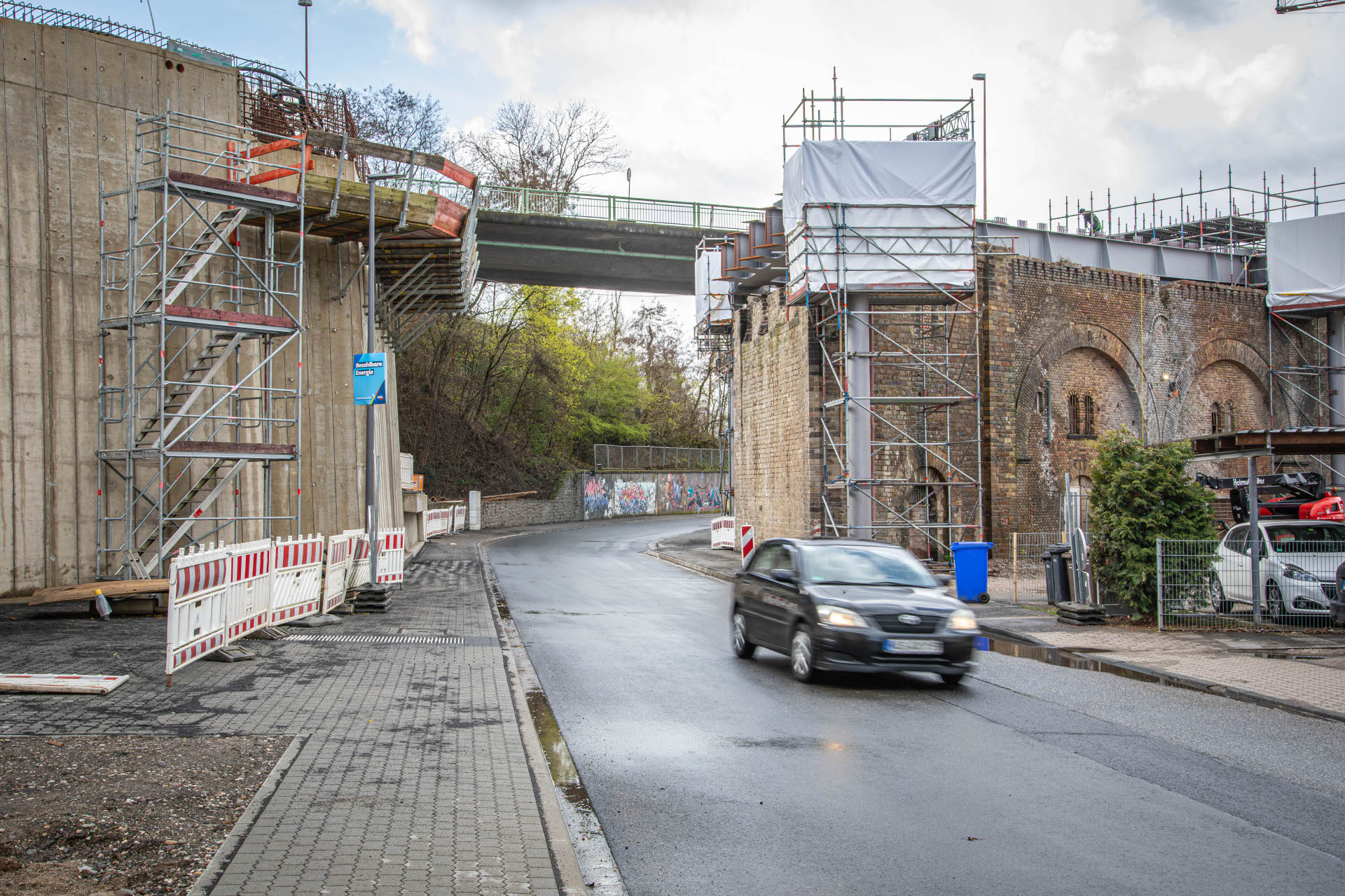 Ein Auto fährt auf einer Straße durch eine Brücke, an der Bauarbeiten stattfinden. Ein Auto fährt auf einer Straße durch eine Brücke, an der Bauarbeiten stattfinden.
