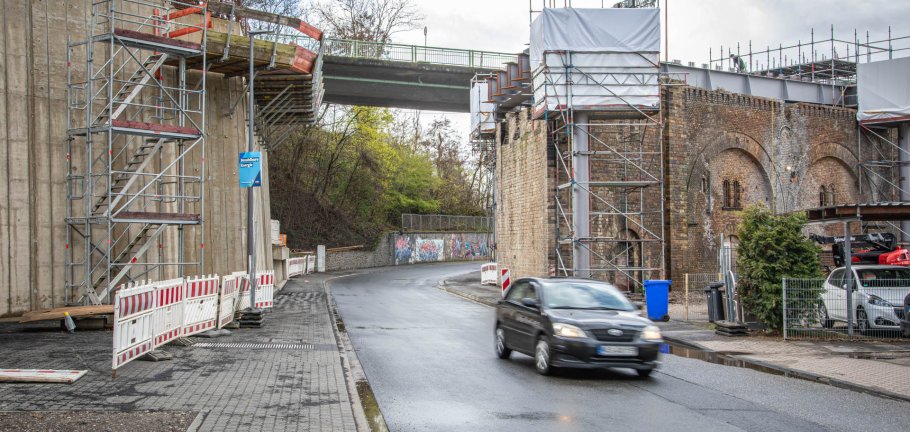 Ein Auto fährt auf einer Straße durch eine Brücke, an der Bauarbeiten stattfinden. Ein Auto fährt auf einer Straße durch eine Brücke, an der Bauarbeiten stattfinden.
