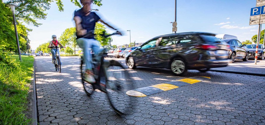 Zwei Fahrradfahrer und ein Auto fahren auf einer Straße. Zwei Fahrradfahrer und ein Auto fahren auf einer Straße.