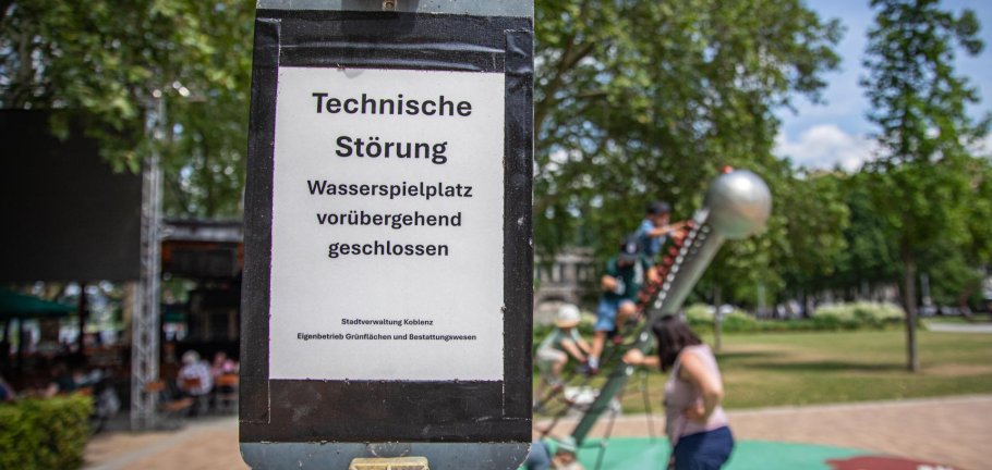 Ein Schild steht an einem Spielplatz und weist auf einen technischen Defekt hin.
