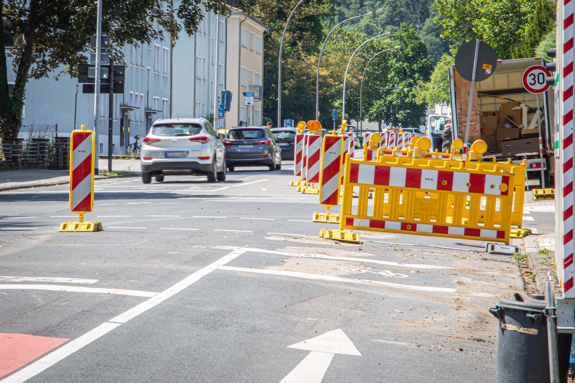 Autos fahren an einer Straßenabsperrung vorbei.