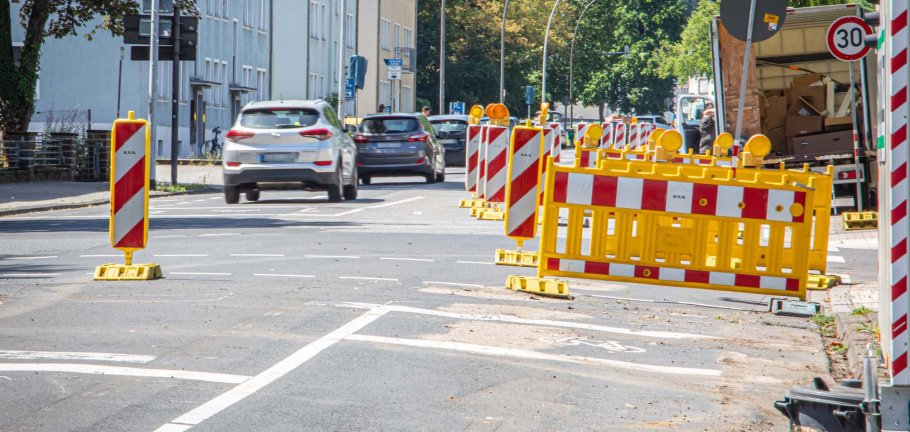 Autos fahren an einer Straßenabsperrung vorbei. Autos fahren an einer Straßenabsperrung vorbei.