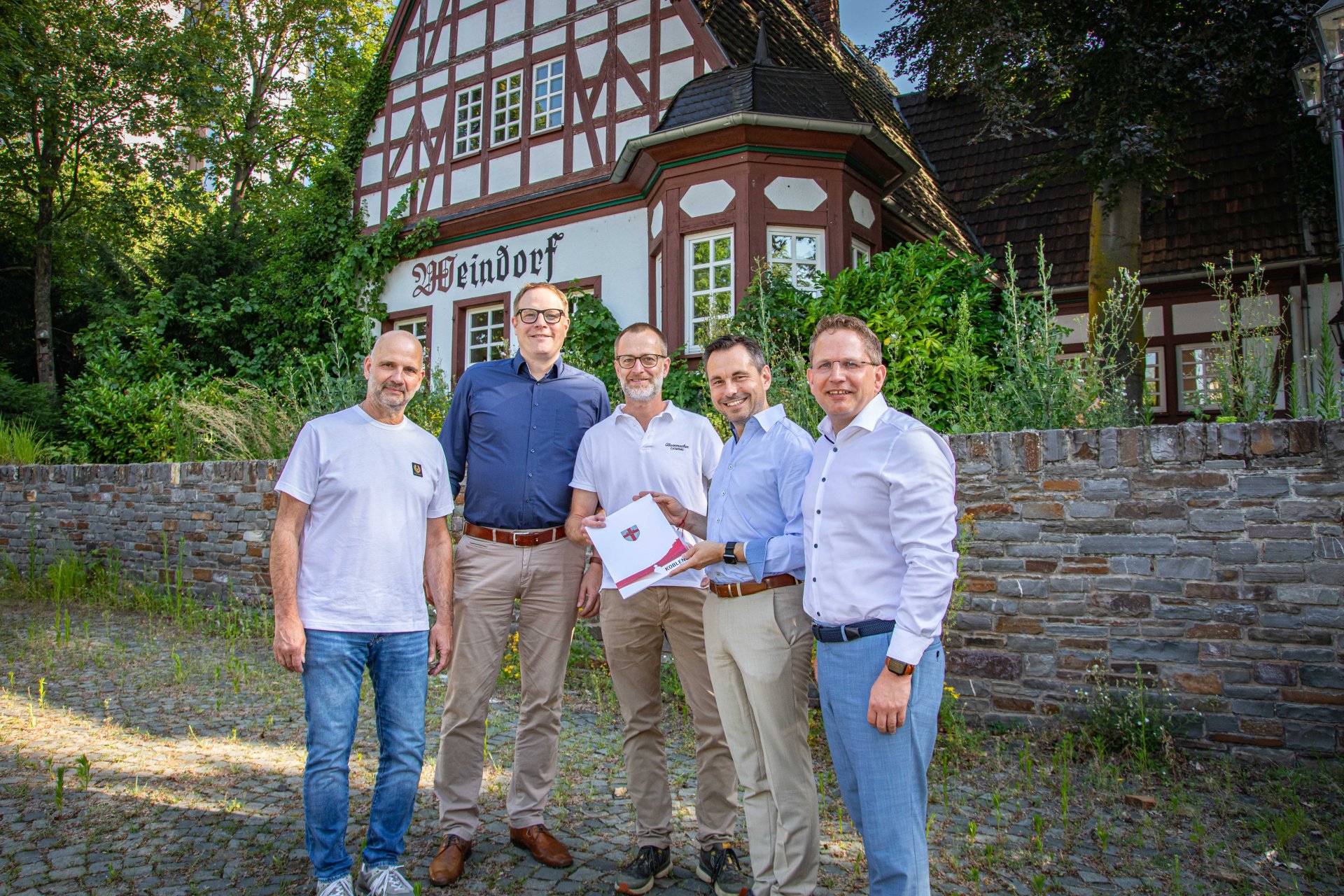 Fünf Männer stehen vor einem Fachwerkgebäude.