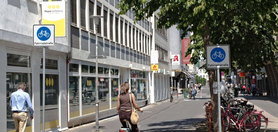 Eine Radfahrerin fährt an einem Straßenschild vorbei, dass eine Fahrradstraße ankündigt. Eine Radfahrerin fährt an einem Straßenschild vorbei, dass eine Fahrradstraße ankündigt.