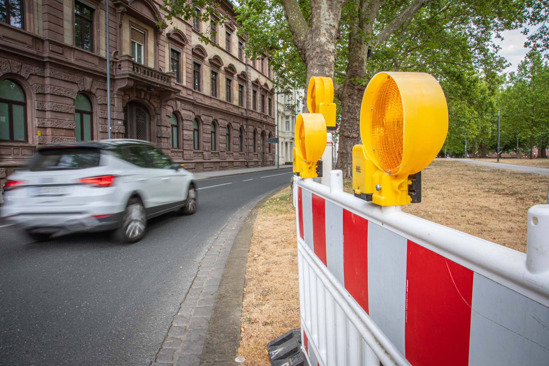 Ein Auto fährt auf einer Straße an einer Absperrung vorbei. Ein Auto fährt auf einer Straße an einer Absperrung vorbei.