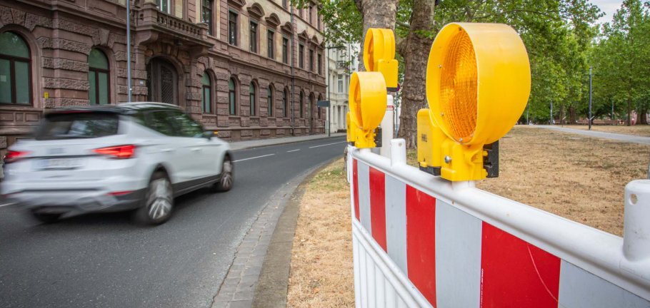 Ein Auto fährt auf einer Straße an einer Absperrung vorbei. Ein Auto fährt auf einer Straße an einer Absperrung vorbei.