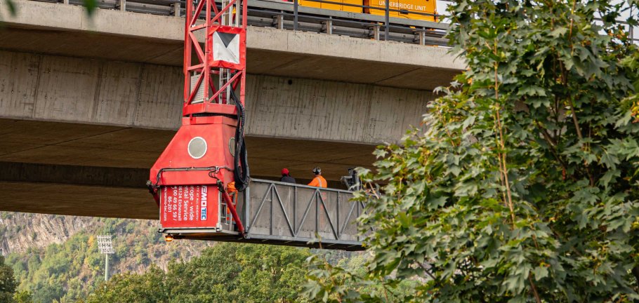 Bauarbeiter kontrollieren von einem Unterflurgerät aus eine Brücke. Bauarbeiter kontrollieren von einem Unterflurgerät aus eine Brücke.