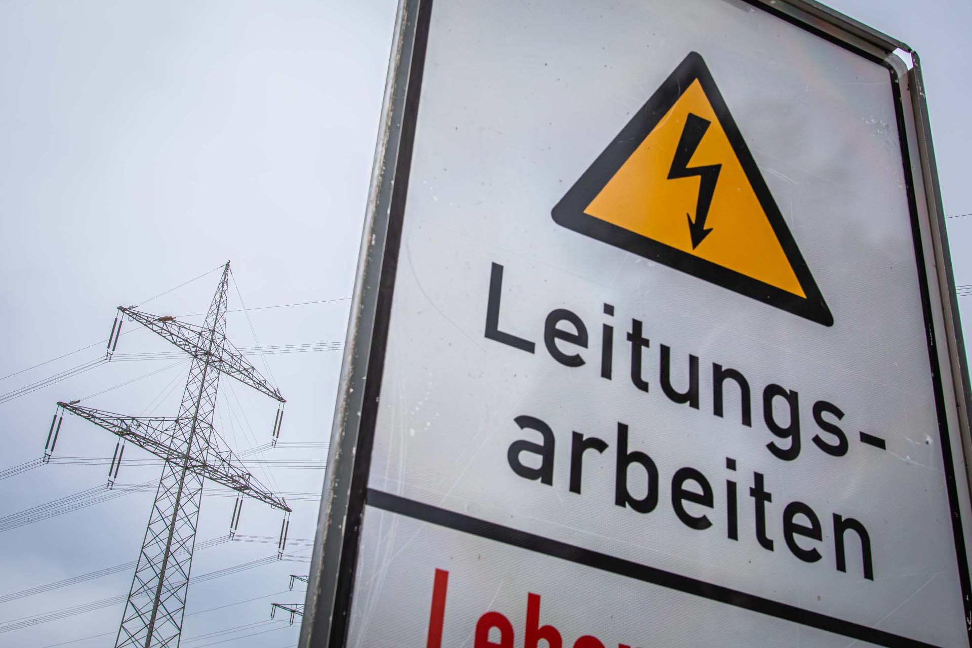 Stromleitungen sind hinter einem Hinweisschild zu sehen.