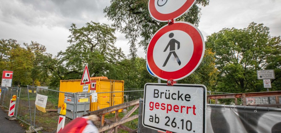 Eine Fahrradfahrerin fährt an einem Hinweisschild für eine Brückensperrung vorbei. Eine Fahrradfahrerin fährt an einem Hinweisschild für eine Brückensperrung vorbei.