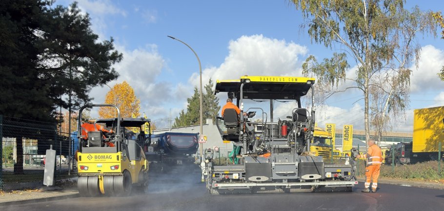 Auf einer Straße wird mit Baumaschinen Asphalt eingebracht.